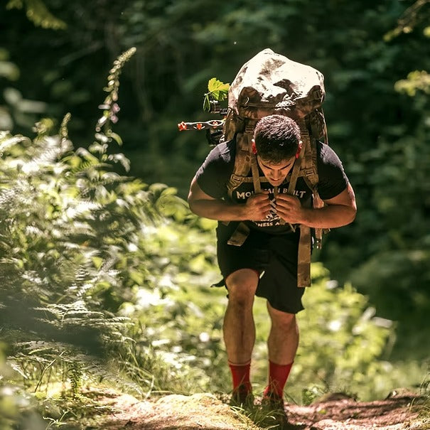 A man hiking uphill under a loaded pack